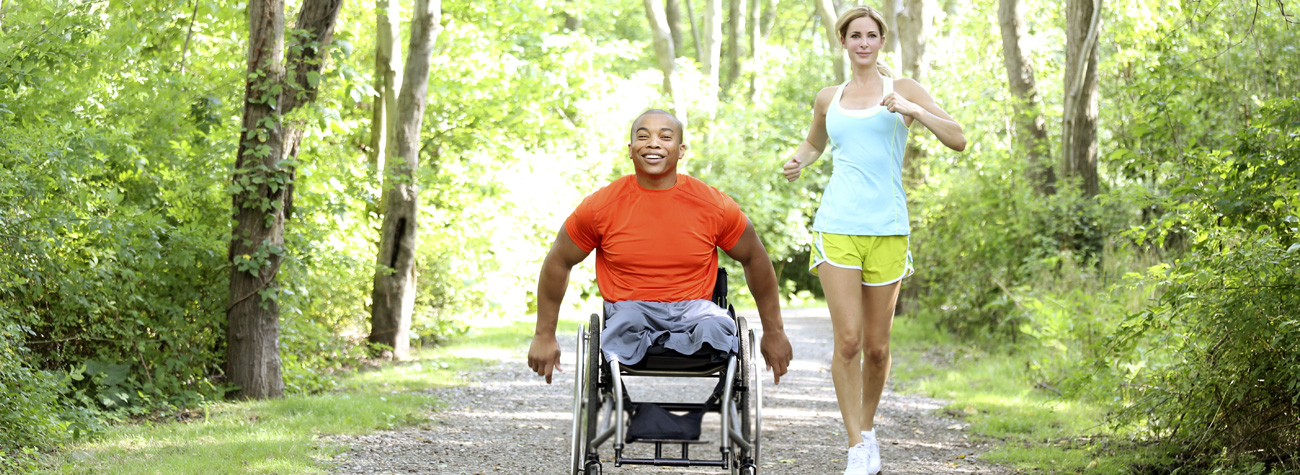 Man in wheelchair with Aquila wheelchair cushion and Woman running alongside